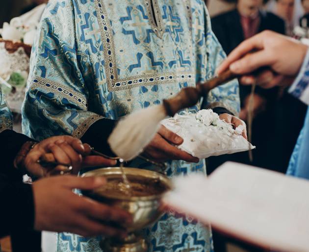 priest blessing wedding rings with holy water for wedding ceremony in church, space for text. religion concept